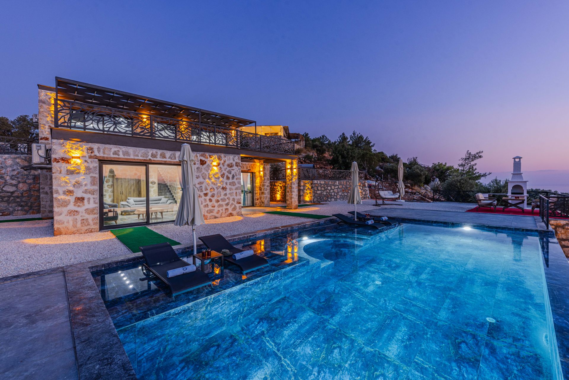 Maison en pierre avec piscine lumineuse, terrasse aménagée et façade ouverte sur l extérieur.