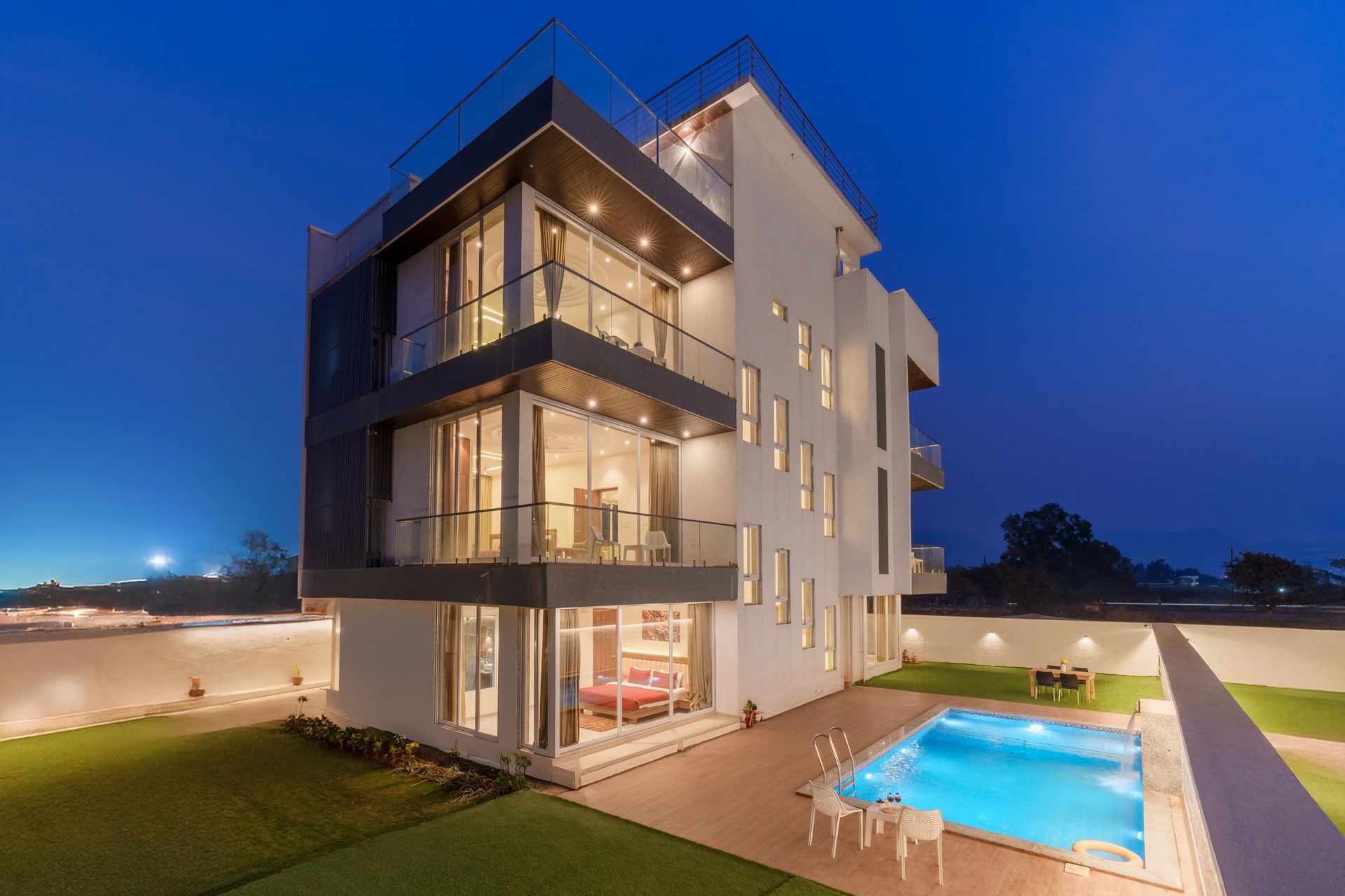 Villa contemporaine avec piscine éclairée au crépuscule.